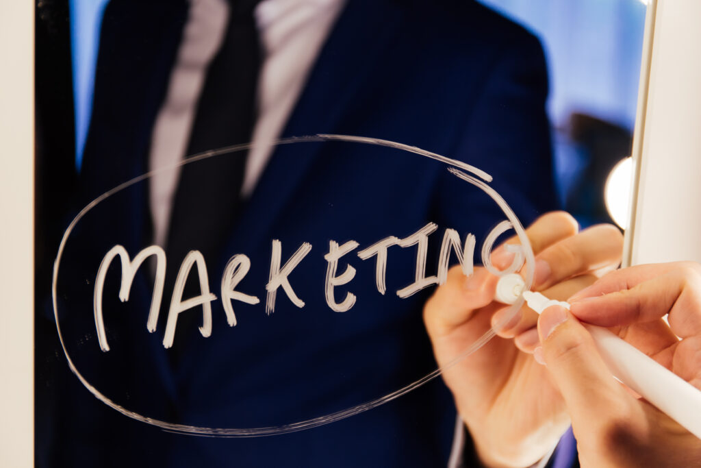 A professional highlighting direct marketing strategy on a glass board during a business planning session.